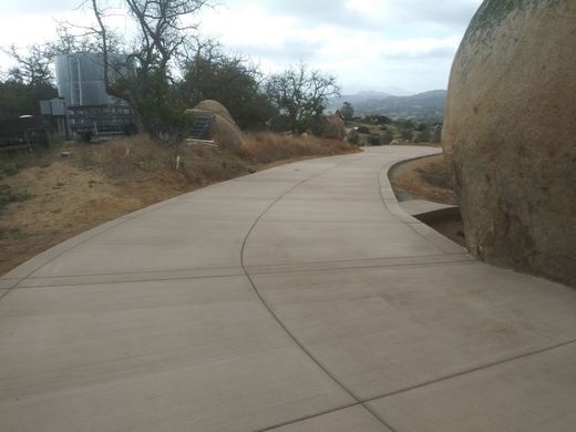 A concrete walkway with a large rock in the background