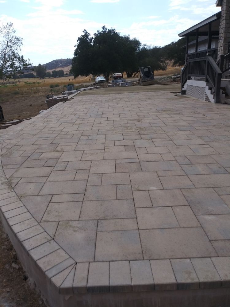 A brick walkway leading to a house with trees in the background