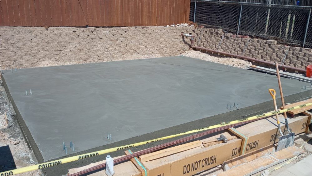 A large concrete slab is being built in a backyard.
