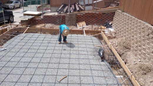 A man wearing a hat is kneeling on a concrete floor.