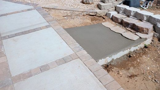 A concrete walkway is being built next to a rock wall.