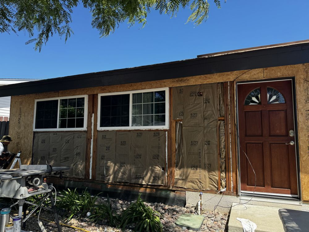 A house with a red door and windows is being remodeled.