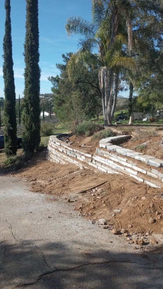 A stone wall is being built next to a dirt road.