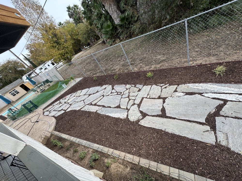 A stone walkway is surrounded by a chain link fence.