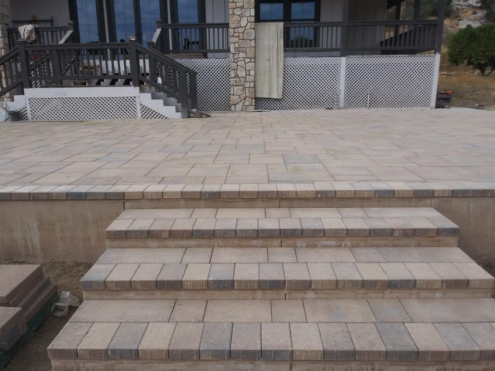 A patio with stairs leading up to it and a house in the background