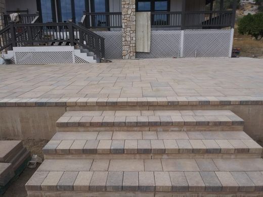 A patio with stairs leading up to it and a house in the background