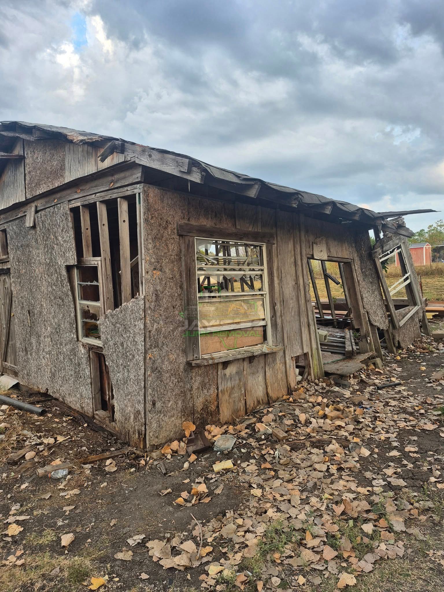 Dilapidated, wooden shack with missing walls and roof, weathered exterior. Overcast sky.