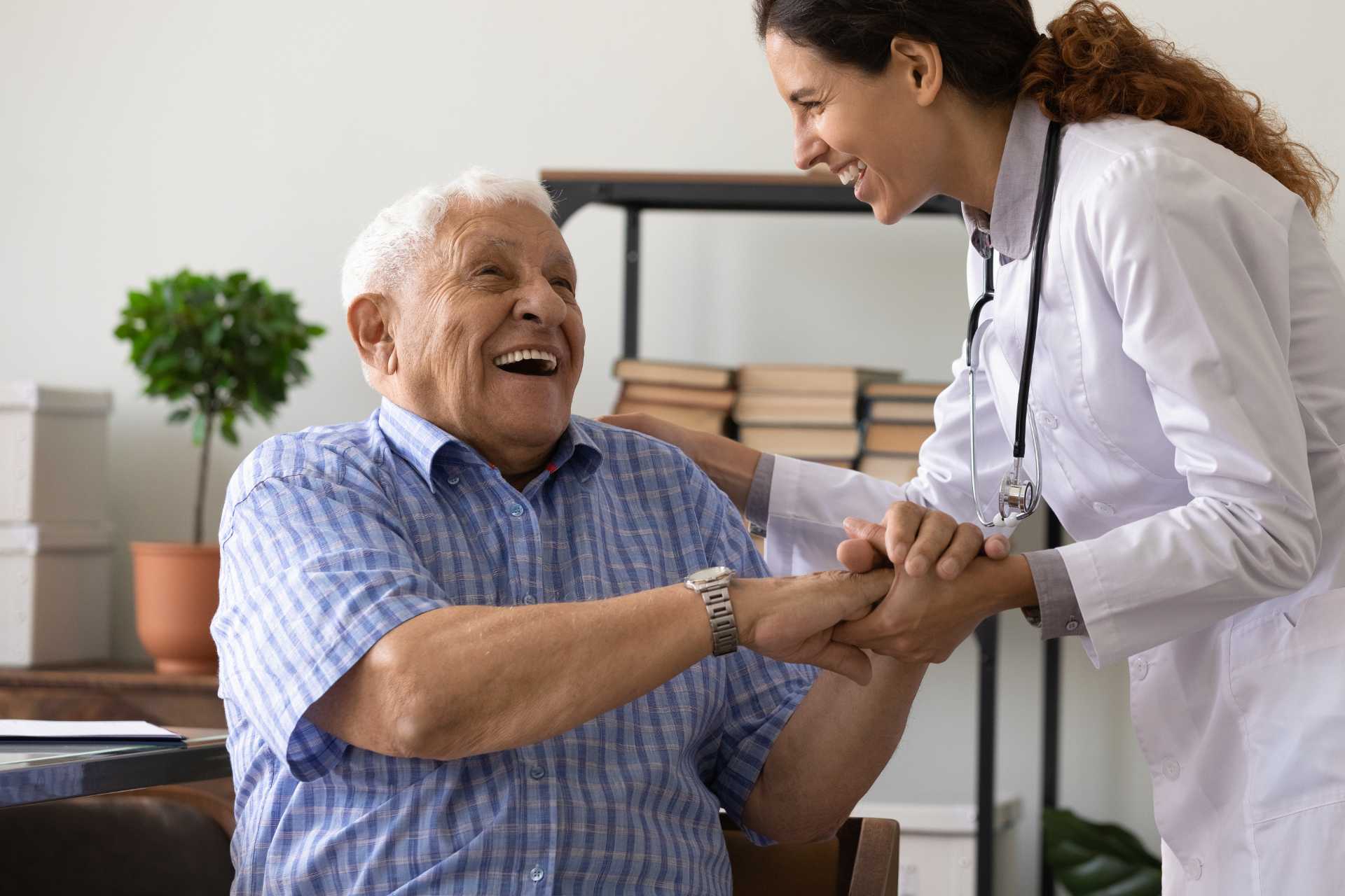 Young woman pushing an elderly woman in a wheelchair along a grassy path in a park.