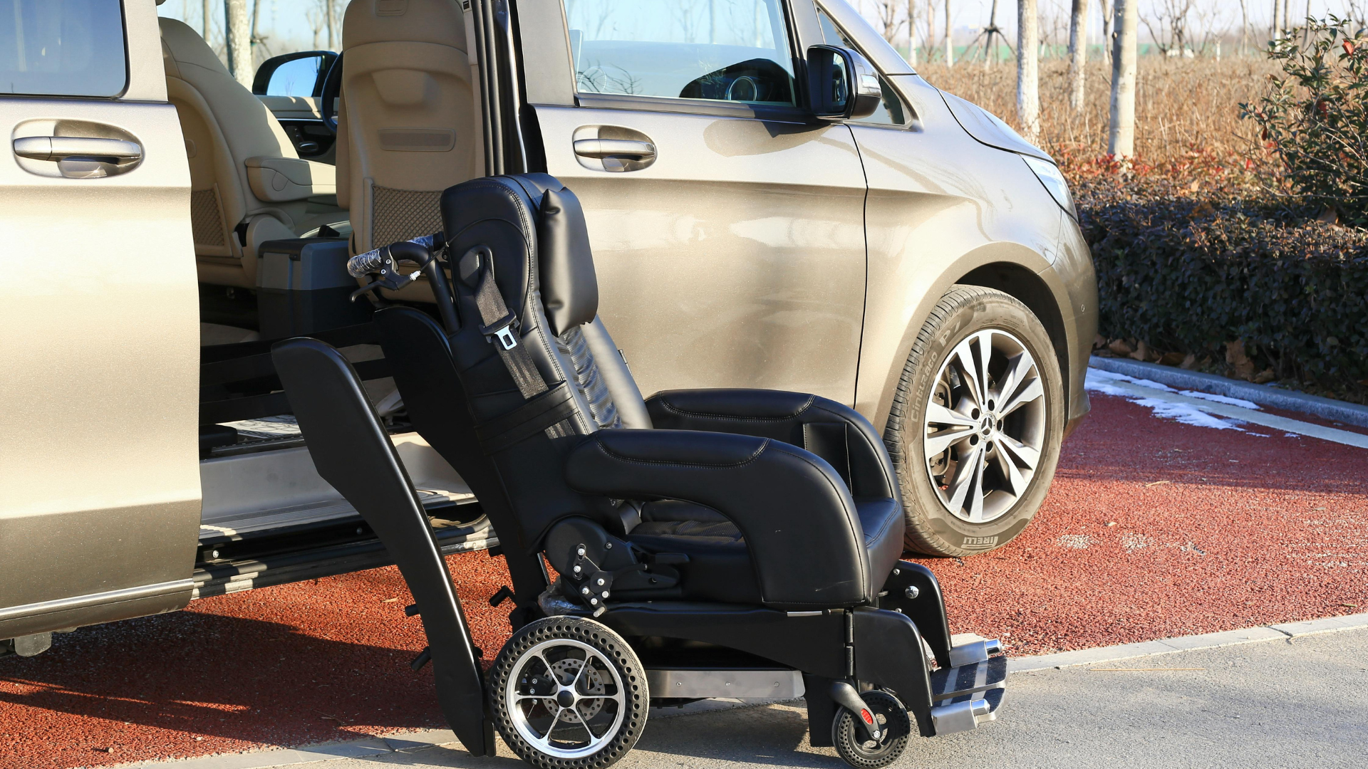 A black wheelchair next to a tan van with an open door.