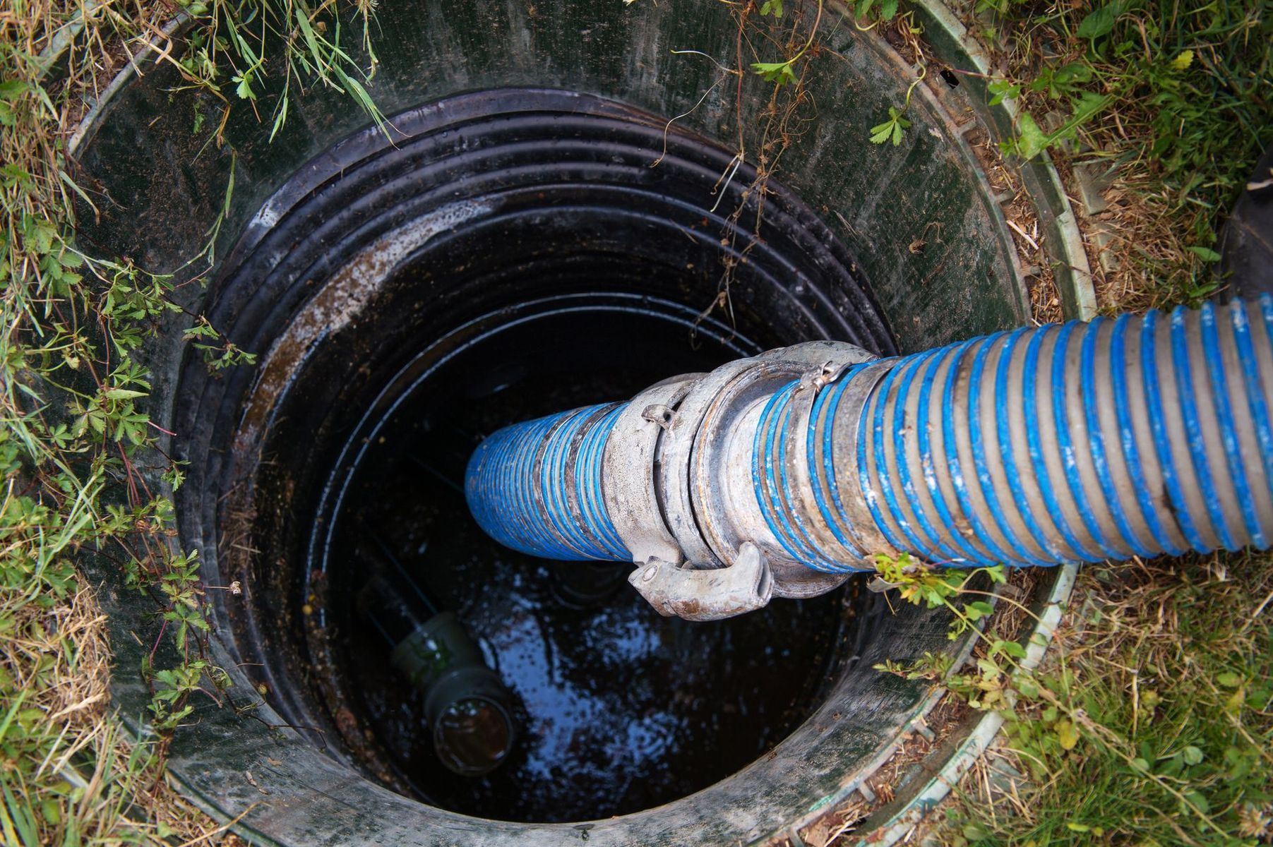 A blue hose is coming out of a septic tank.