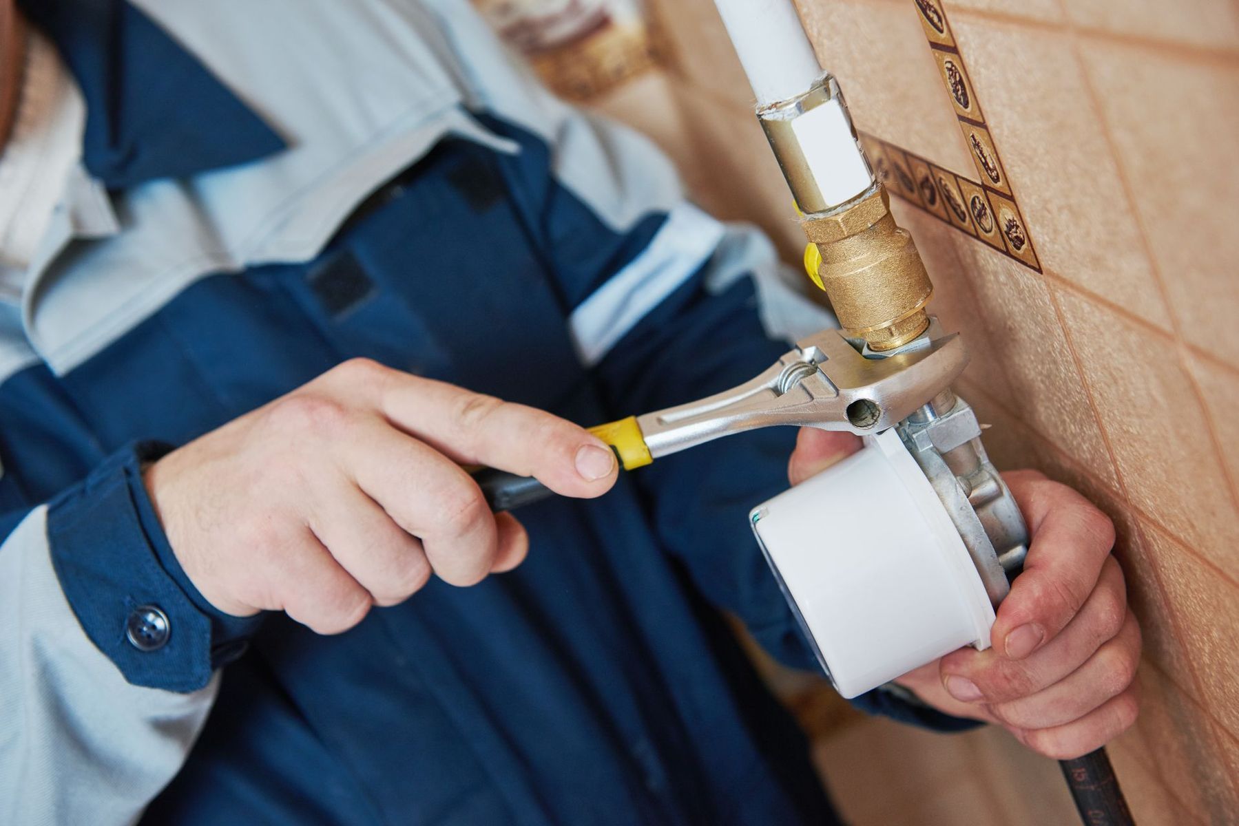 A man is fixing a pipe with a wrench.