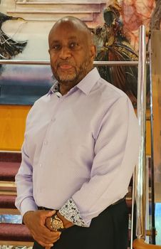Agency owner Ronald Rivers wears a light purple shirt and smiles.