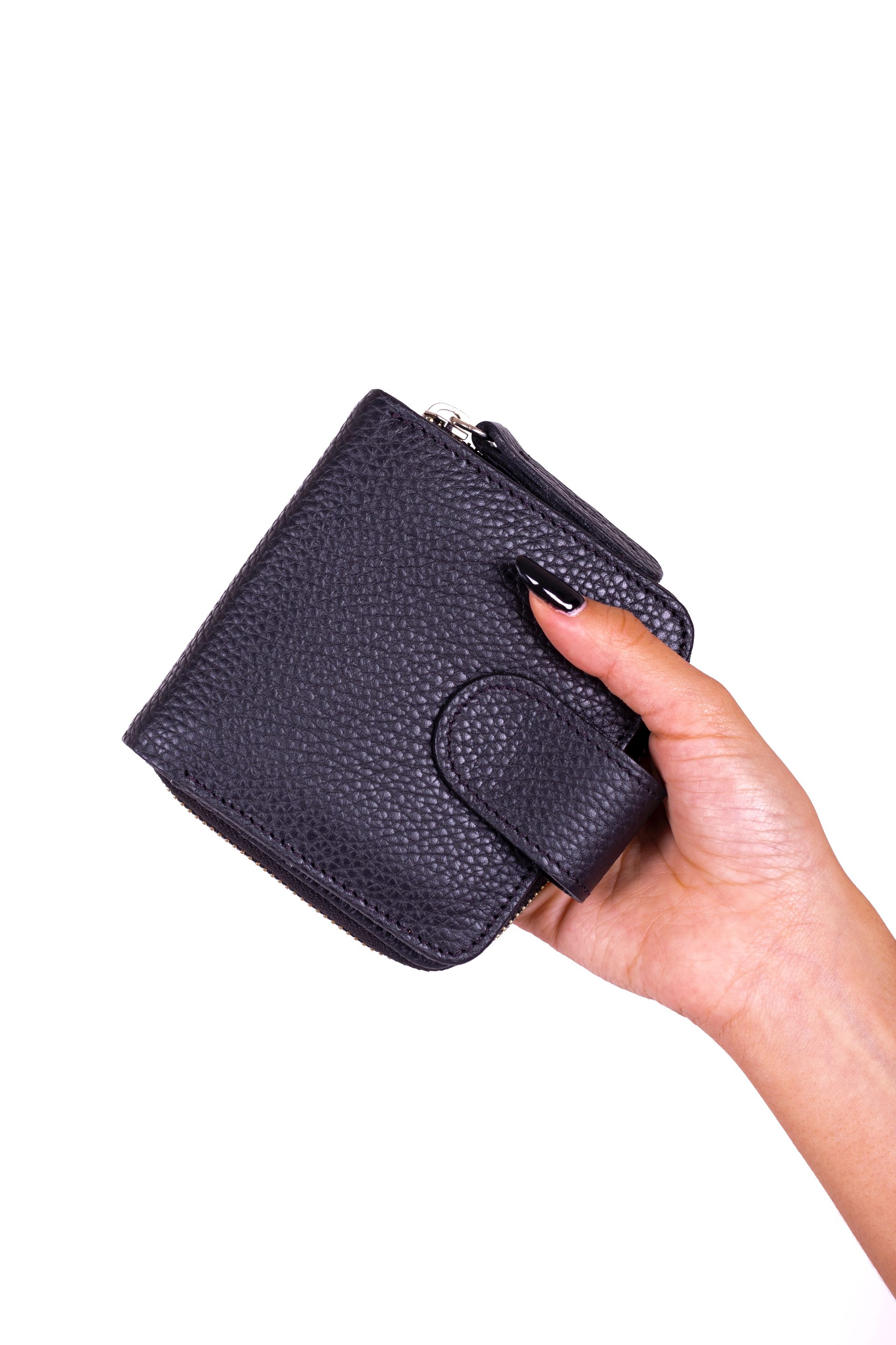 Mano sosteniendo una billetera negra texturizada con cierre de botón.