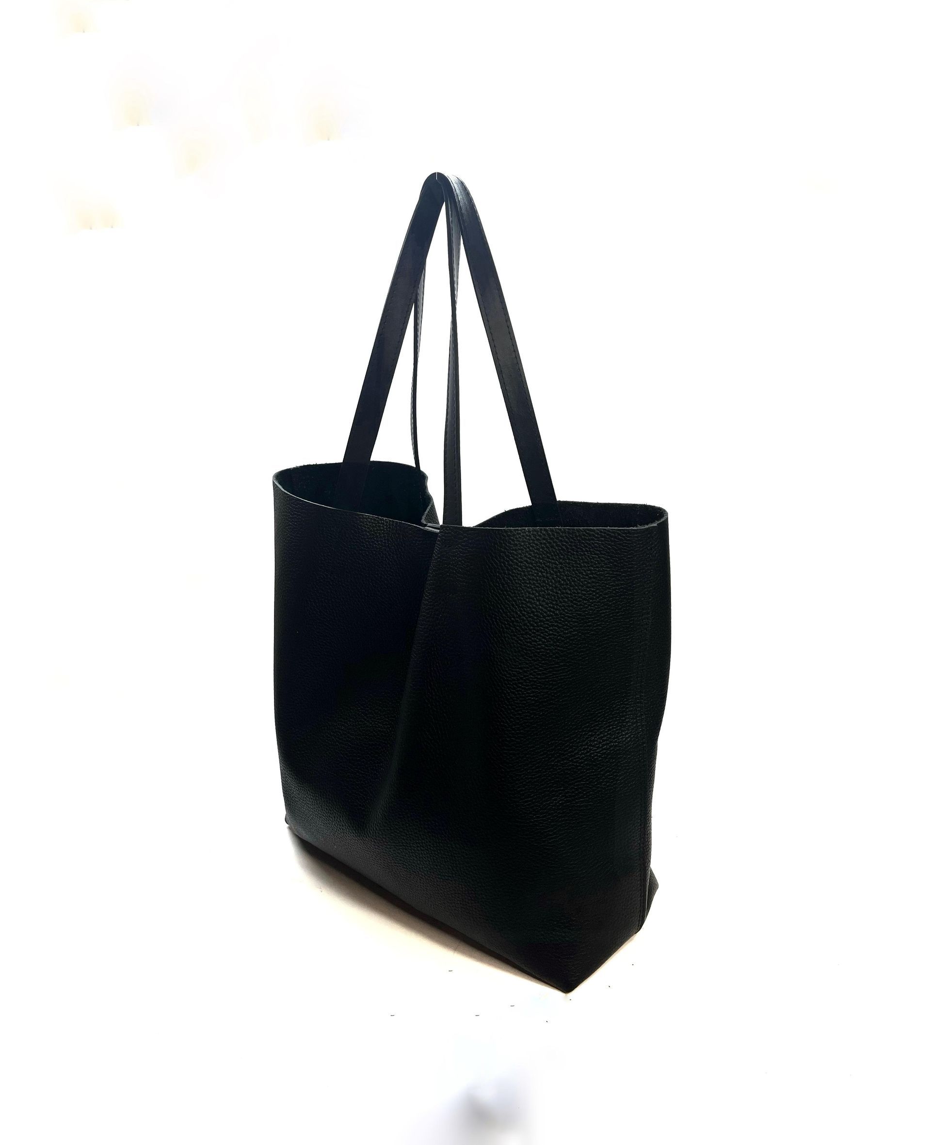 Bolso de mano negro con asas largas sobre fondo blanco.