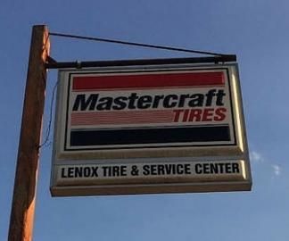 Sign for Mastercraft Tires at Lenox Tire & Service Center, red and black logo against a blue sky.