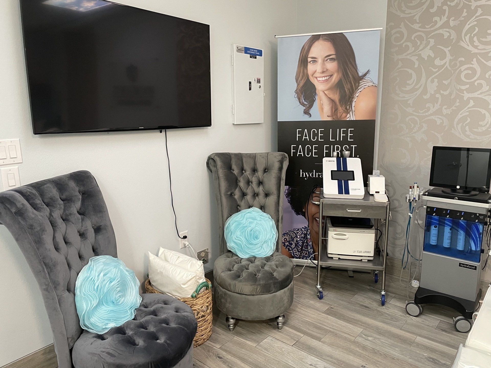 A waiting room with chairs , a television , and a sign on the wall.