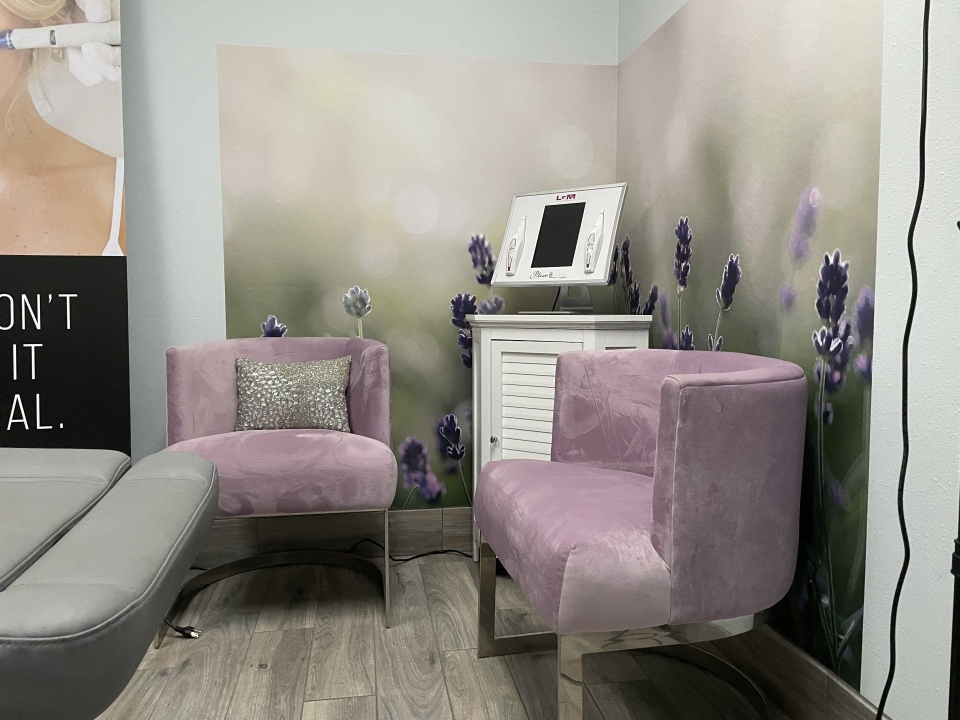 A waiting room with two purple chairs and a sign on the wall.