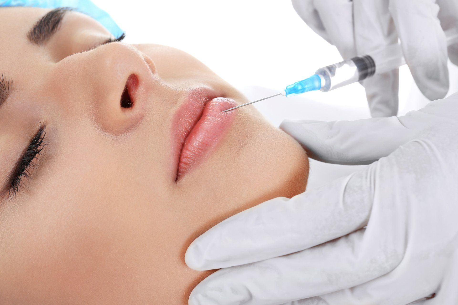 A woman is getting a botox injection in her lips.