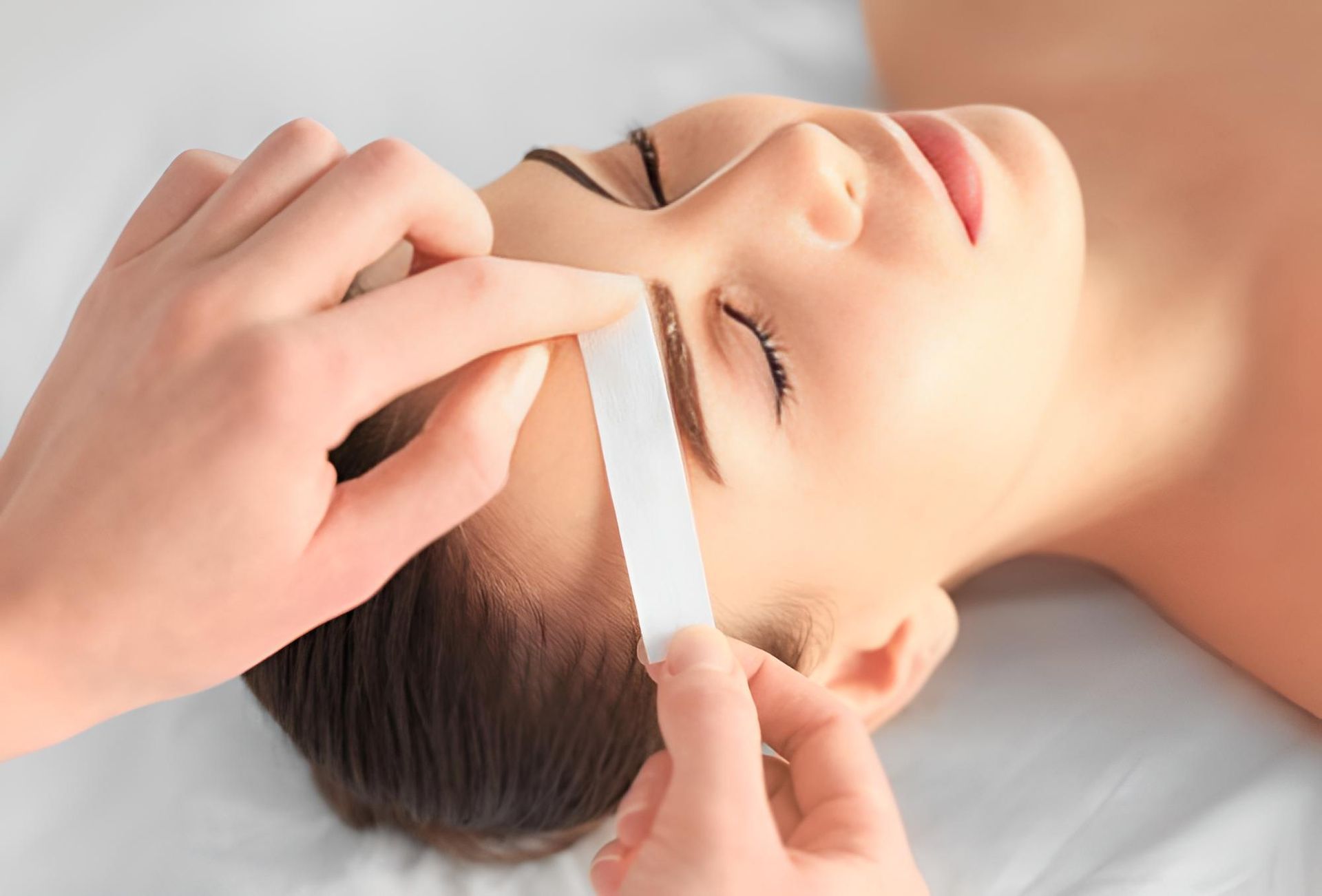 A Woman is Getting Her Eyebrows Waxed at a Beauty Salon — Nonny Thai Healing Massage In Coffs Harbour, NSW
