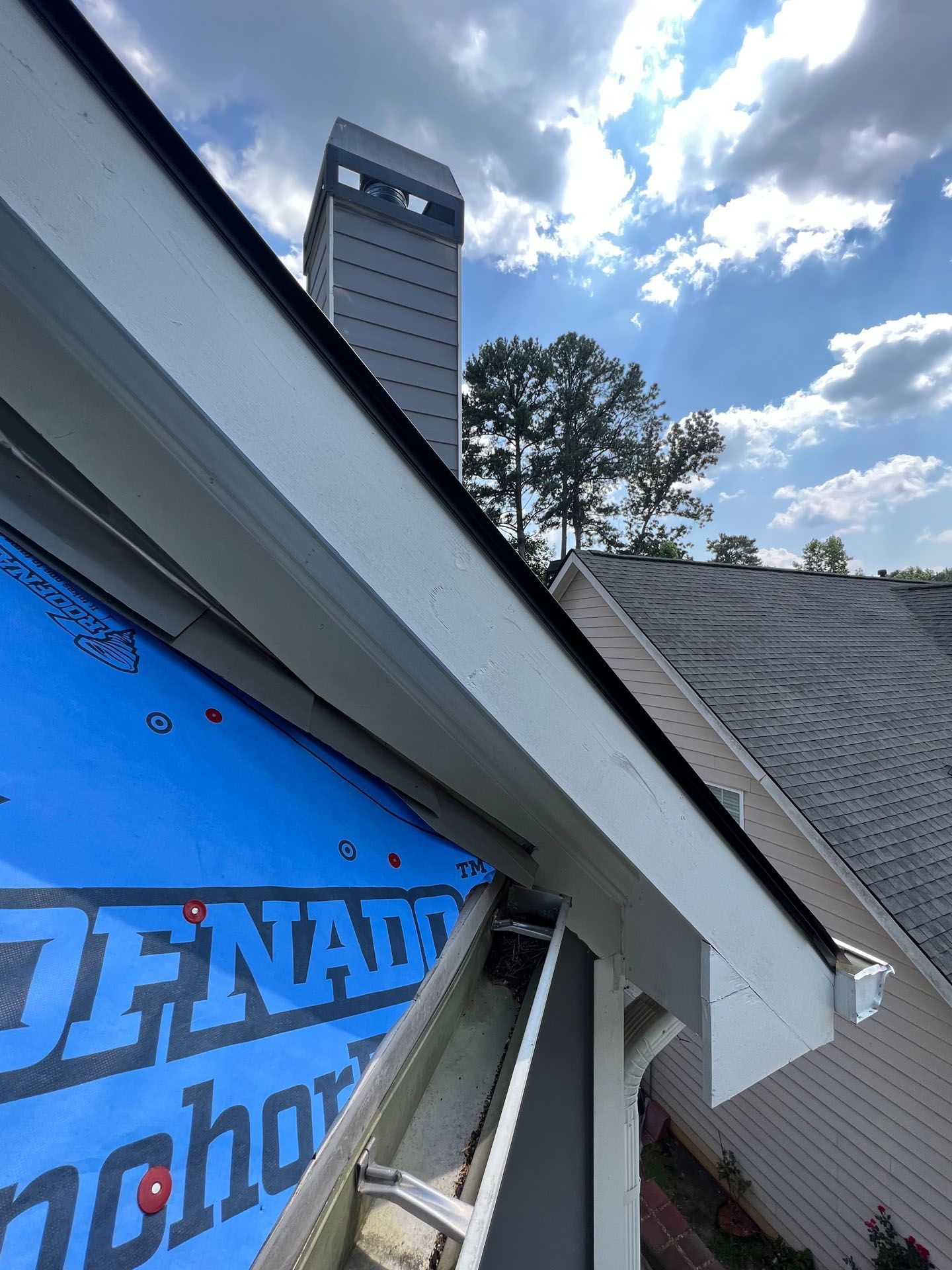 A roof with a blue tarp on it that says tornado anchor