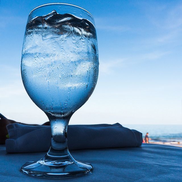 A glass of water is sitting on a table next to a napkin.