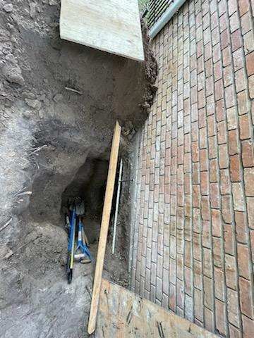 A brick wall with a hole in it and a wooden stick in it.