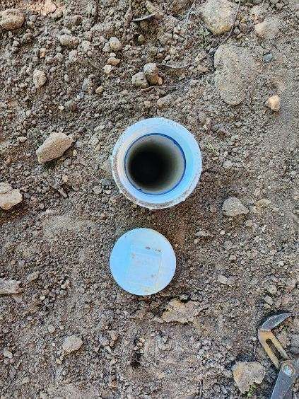 A plastic pipe is sitting on top of a pile of dirt.