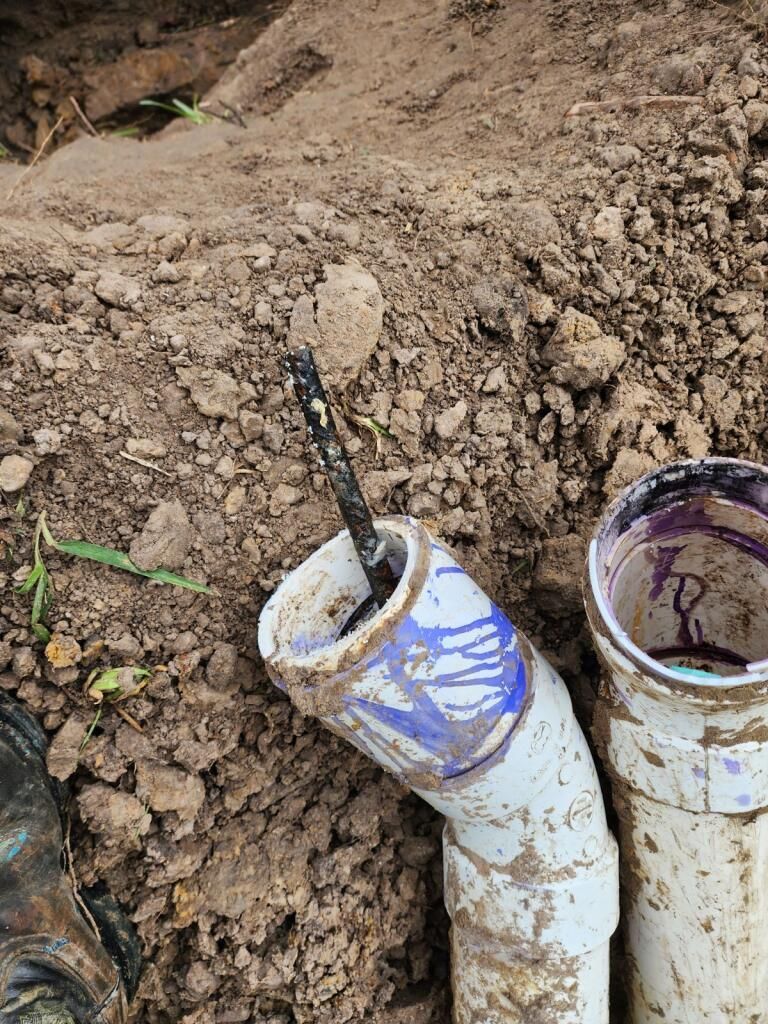Two muddy pipes are sitting on top of a pile of dirt.