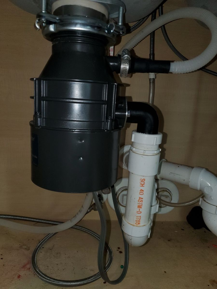 A garbage disposal is sitting under a sink in a kitchen.