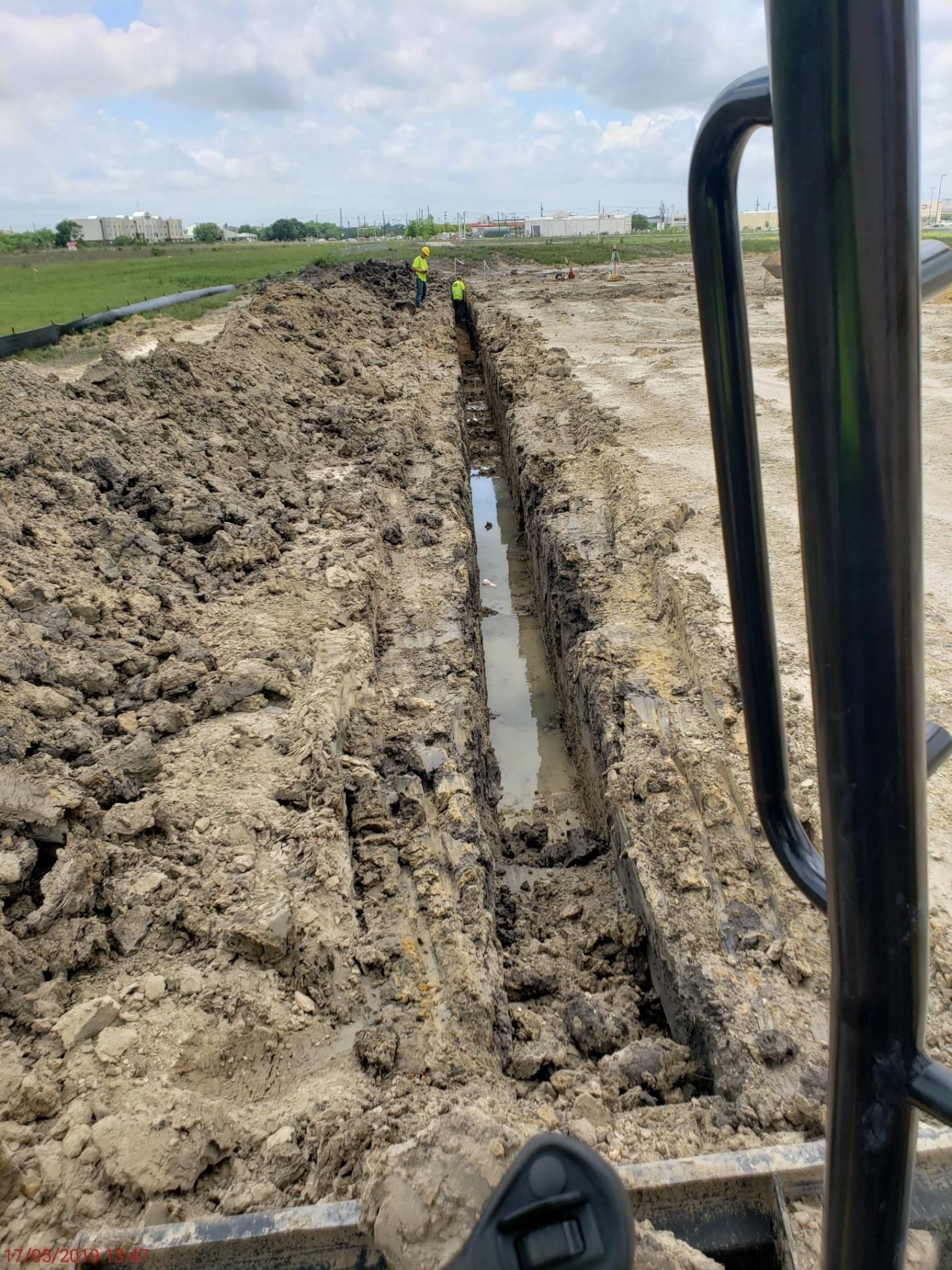 A tractor is digging a trench in the dirt in a field.