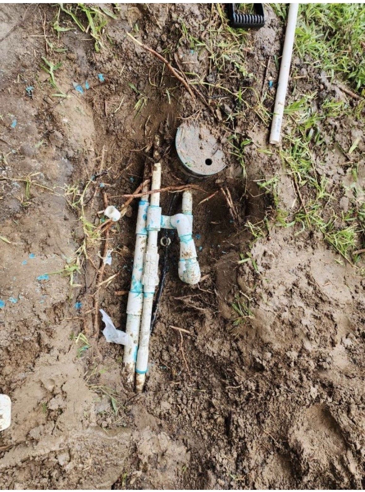 A bunch of pipes are laying in the dirt.