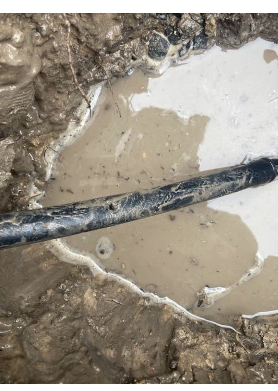 A muddy puddle with a pipe in it.