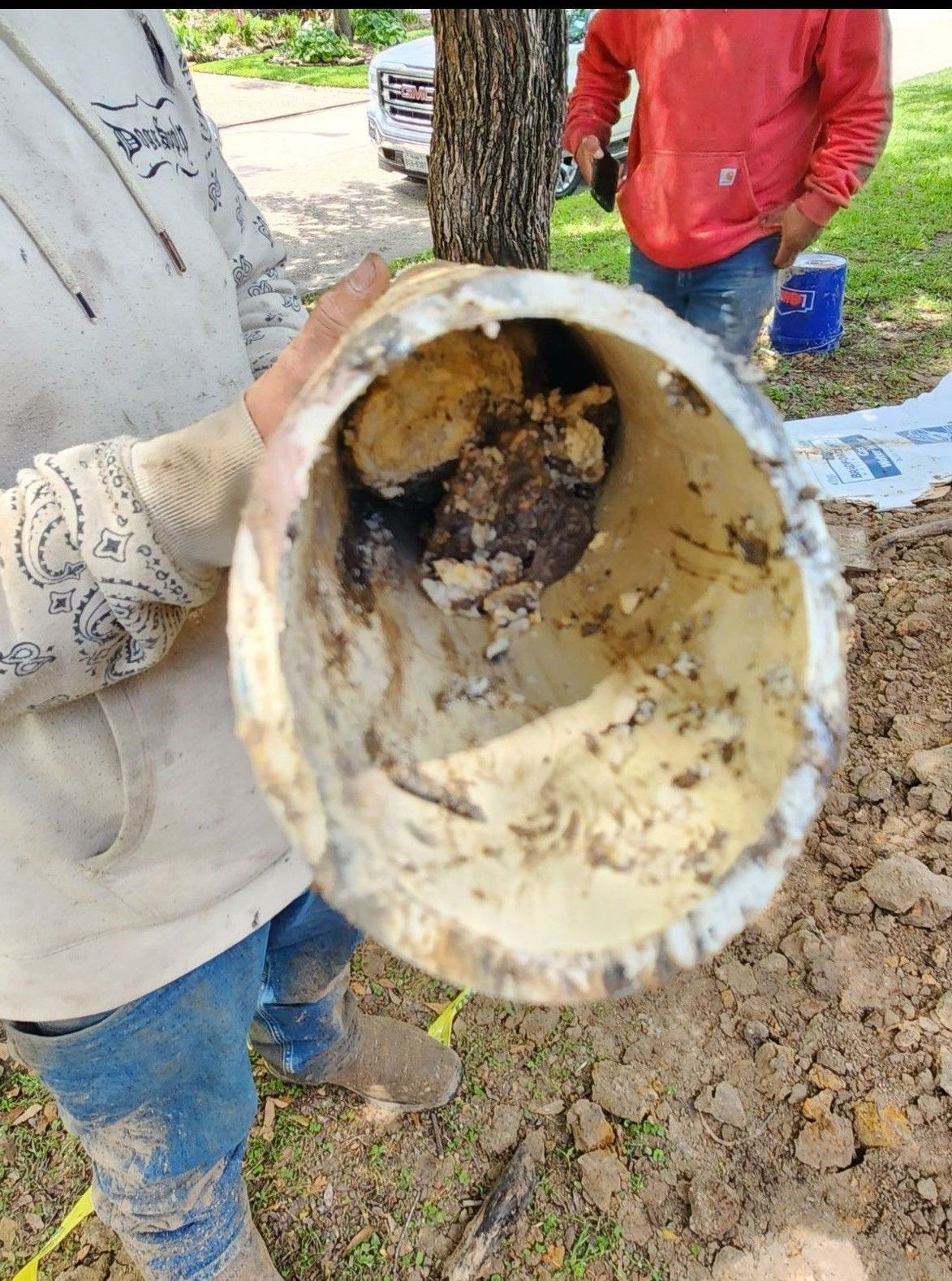 A person is holding a dirty pipe with a hole in it.