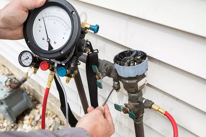 A man is holding a pressure gauge next to a pipe.