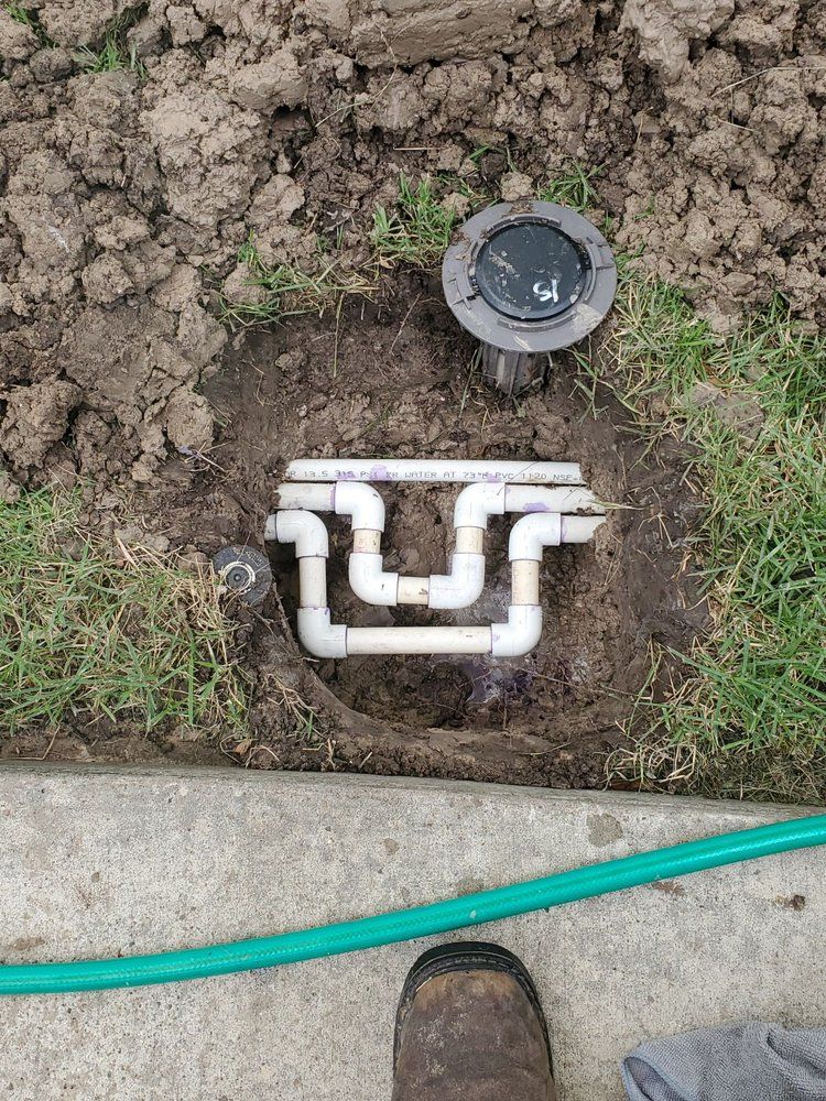 A person is standing next to a hose and a pipe in the dirt.
