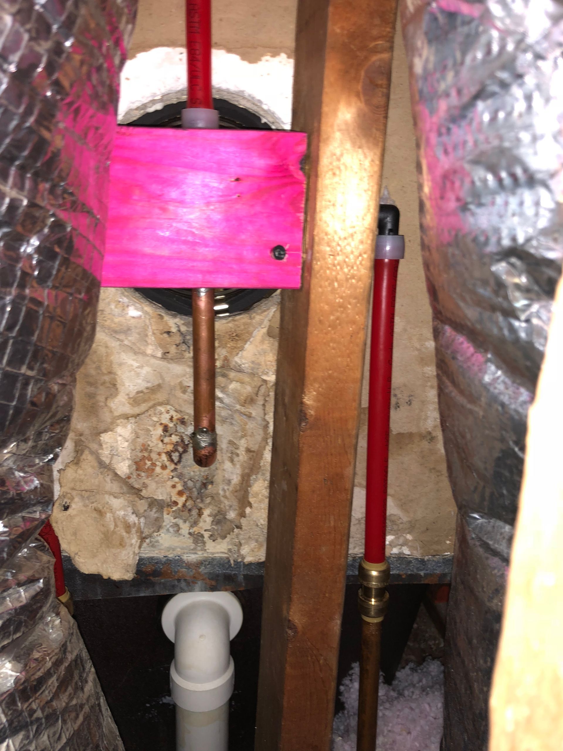 A pink block is sitting on top of a copper pipe.