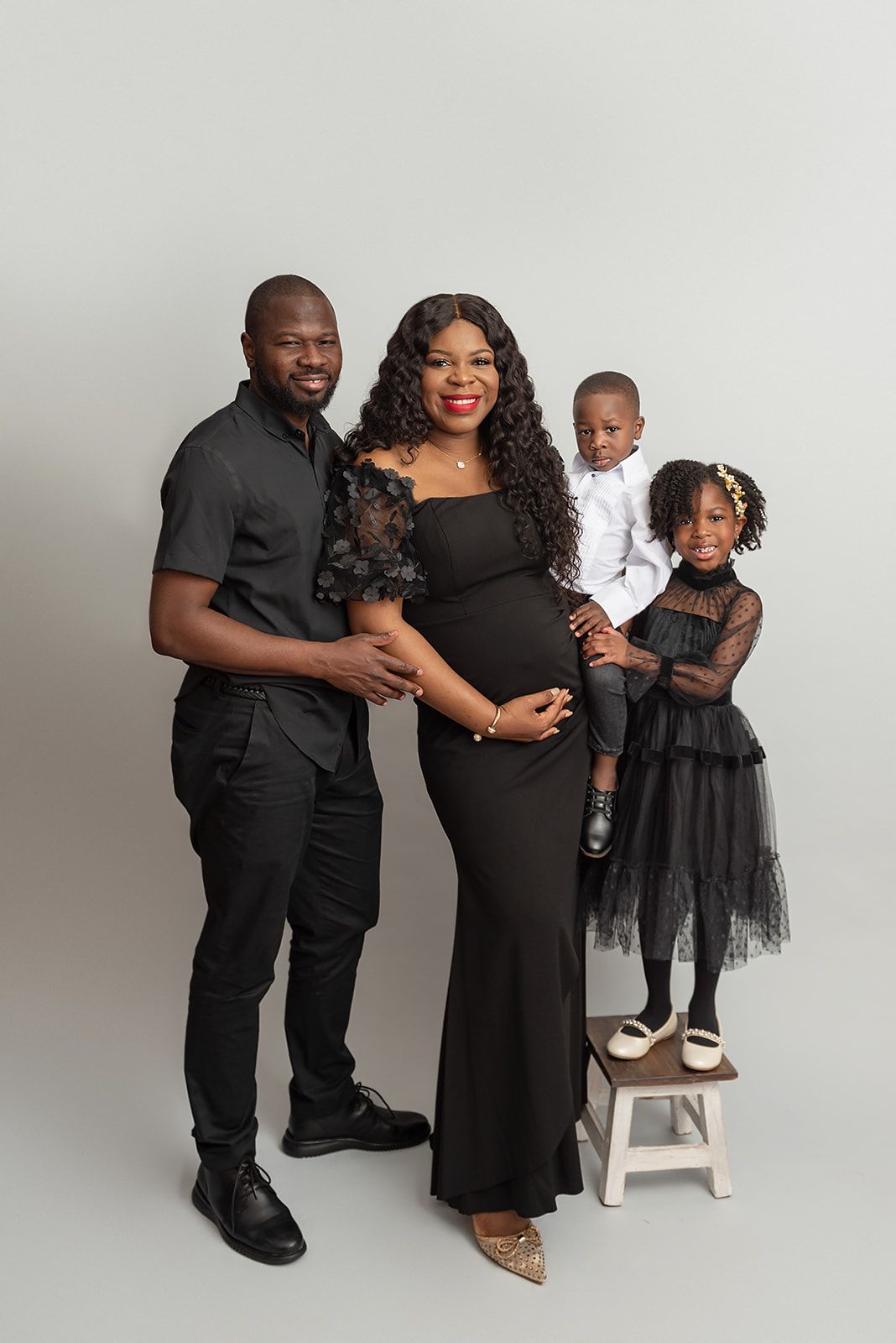 a pregnant woman is posing for a picture with her husband and two children .