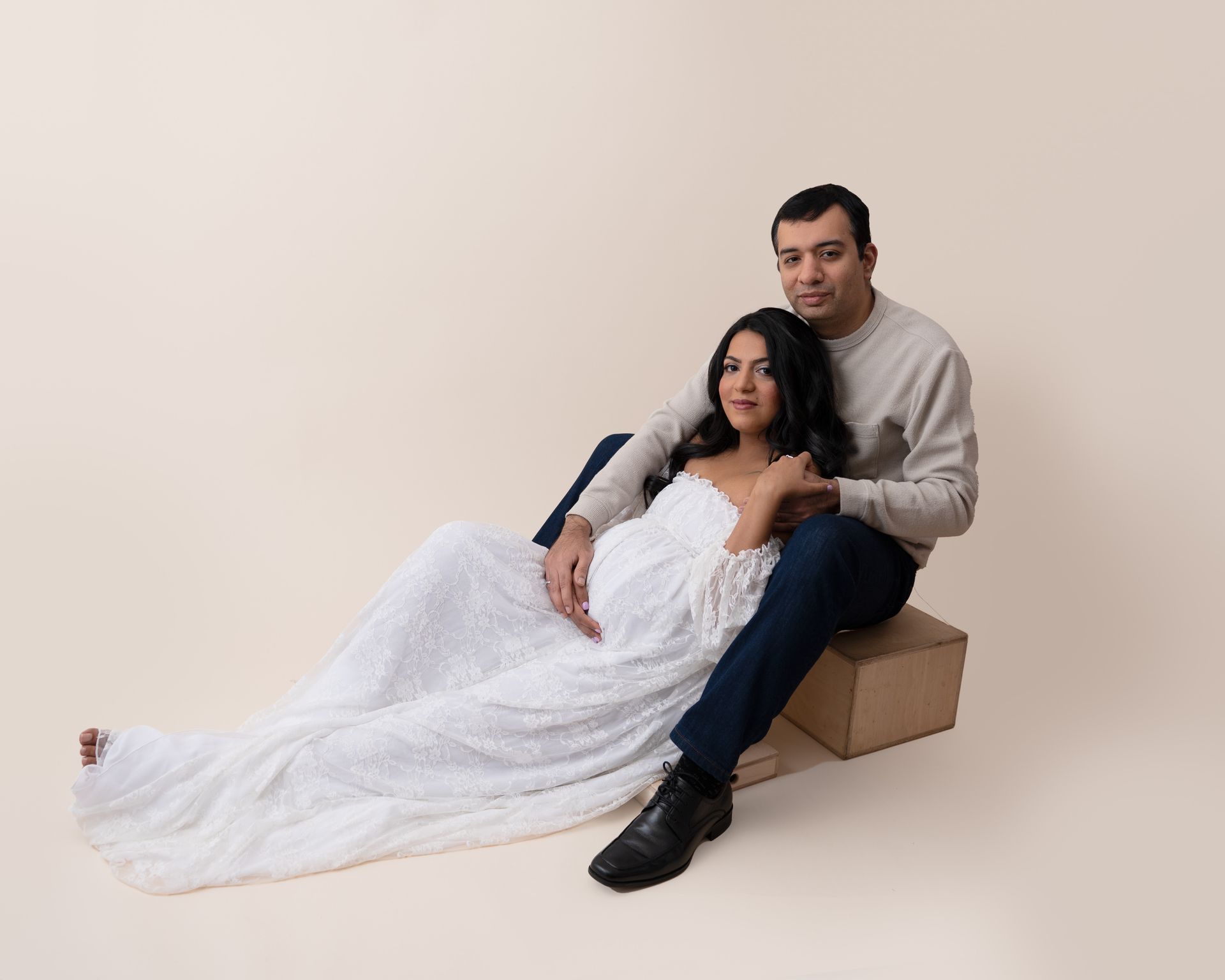 a man and a pregnant woman are sitting next to each other on a box .
