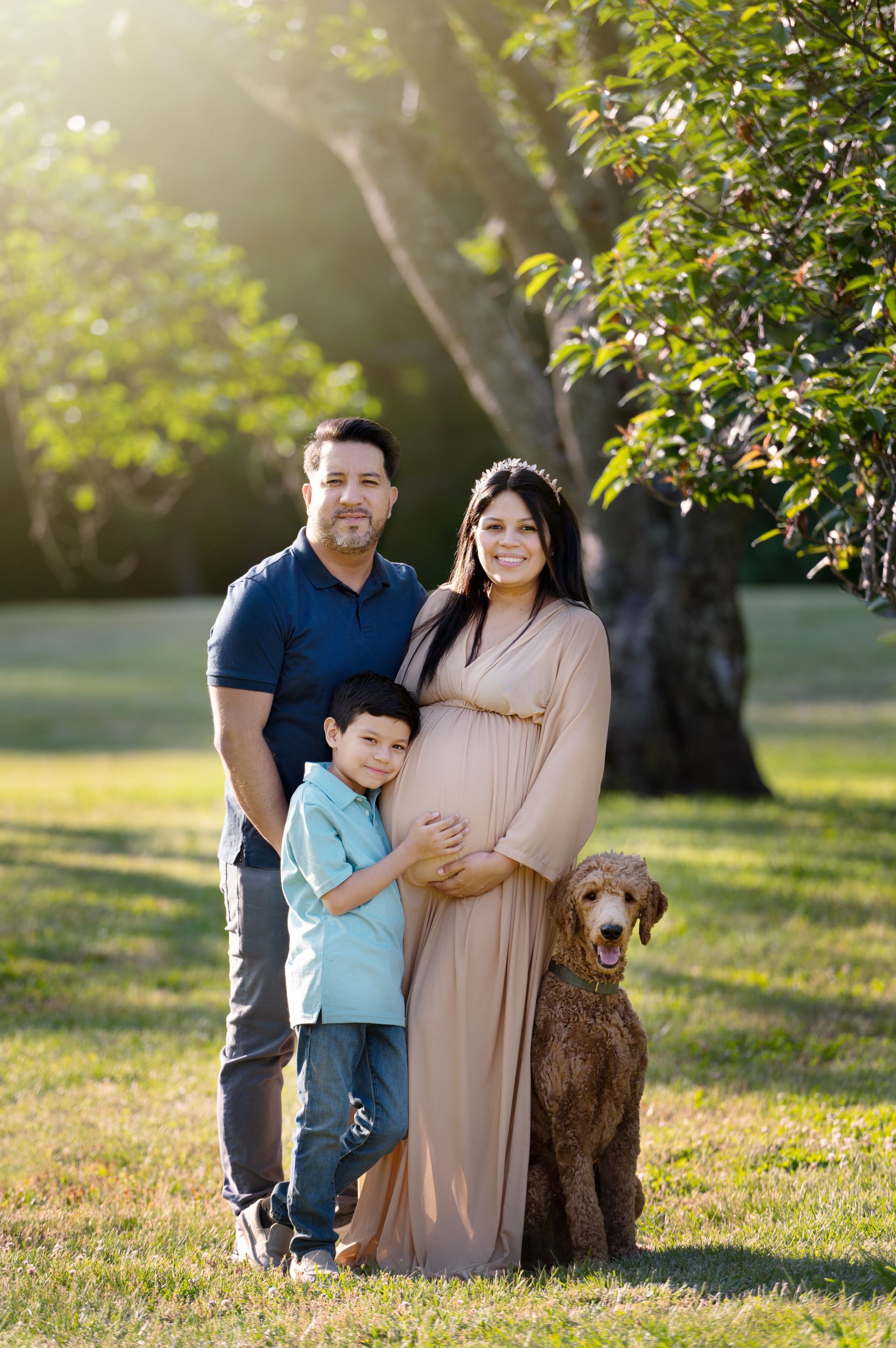 a pregnant woman is posing for a picture with her husband , son and dog .