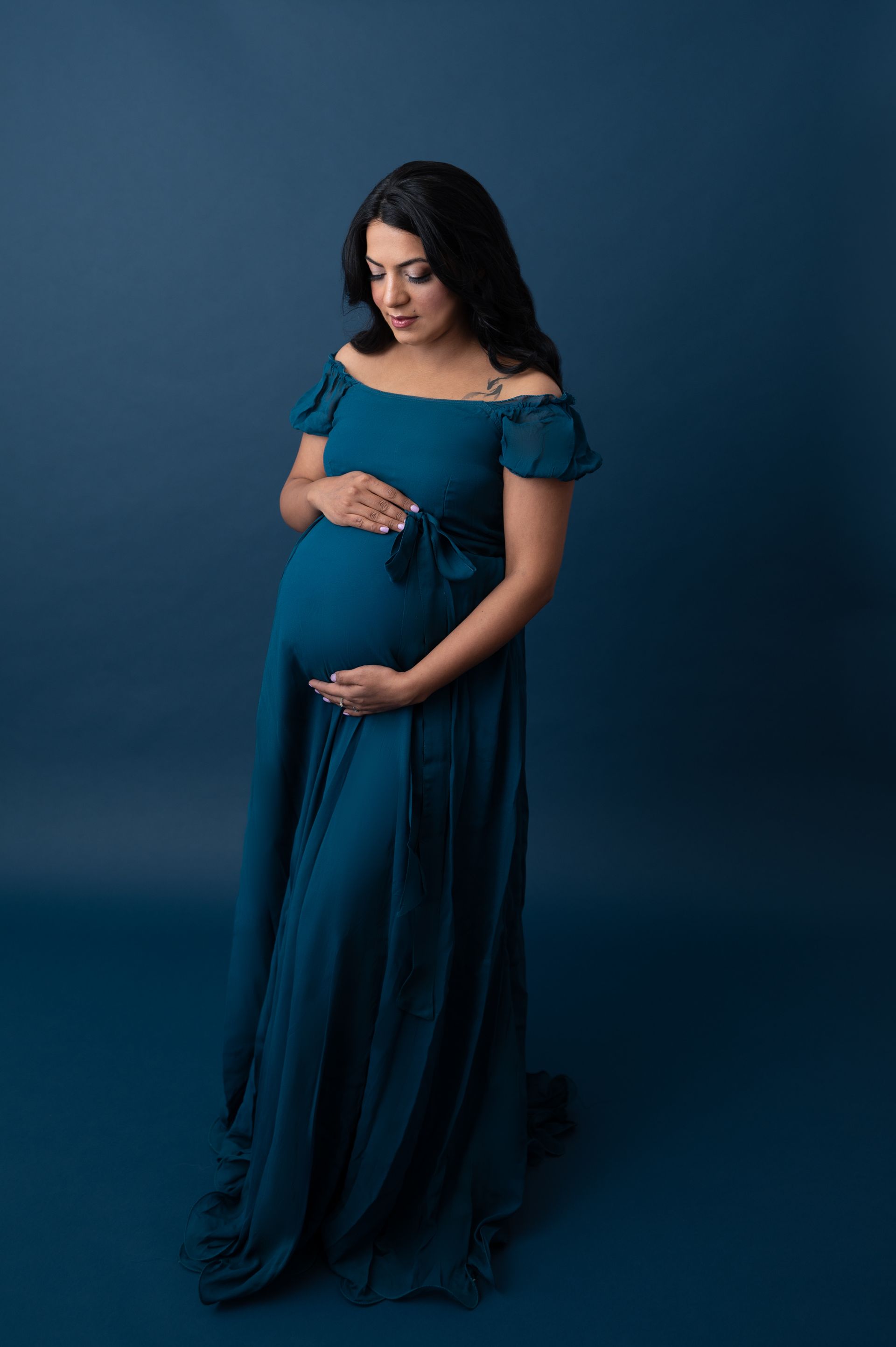 a pregnant woman in a blue dress is holding her belly .