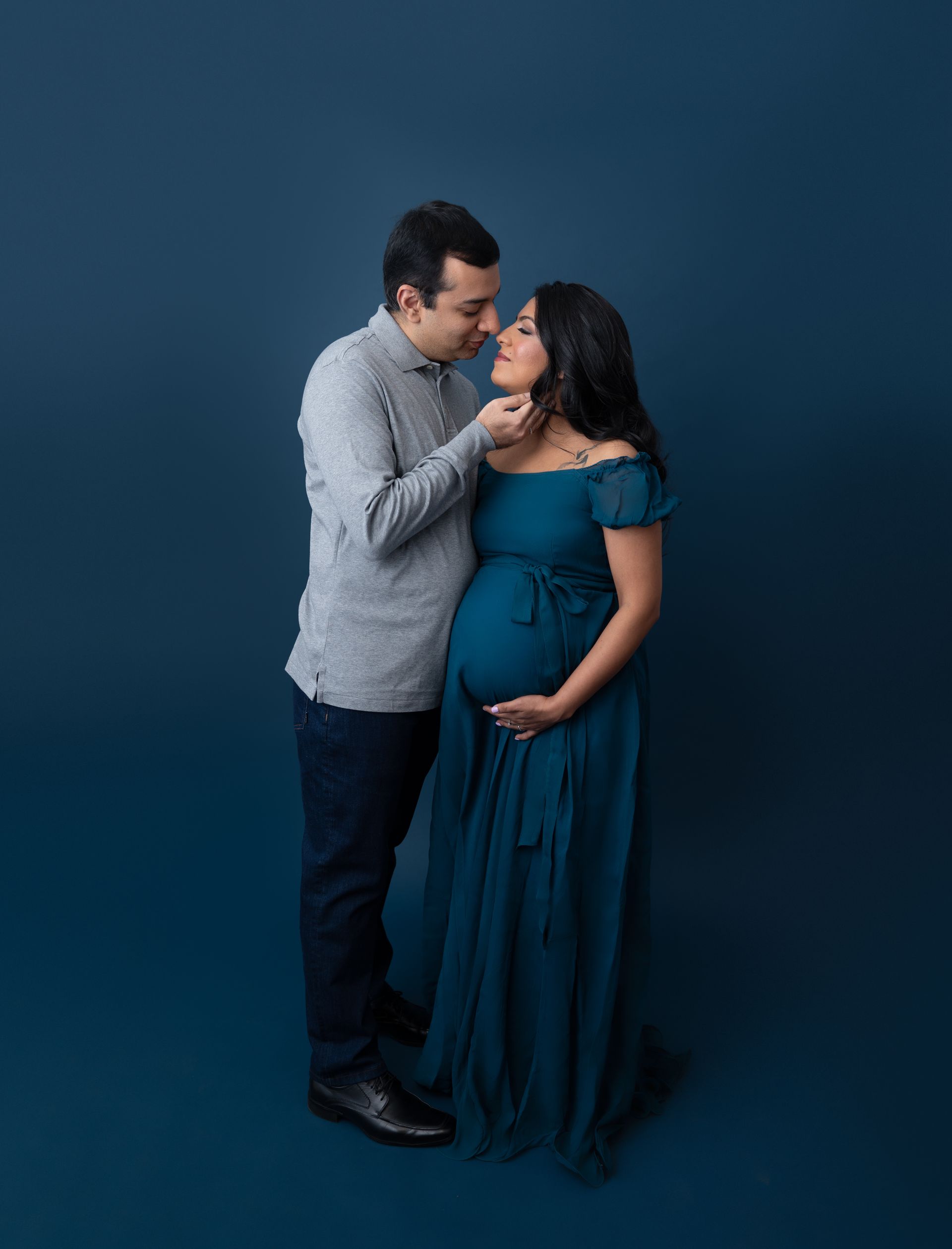 a man is kissing a pregnant woman on the forehead .
