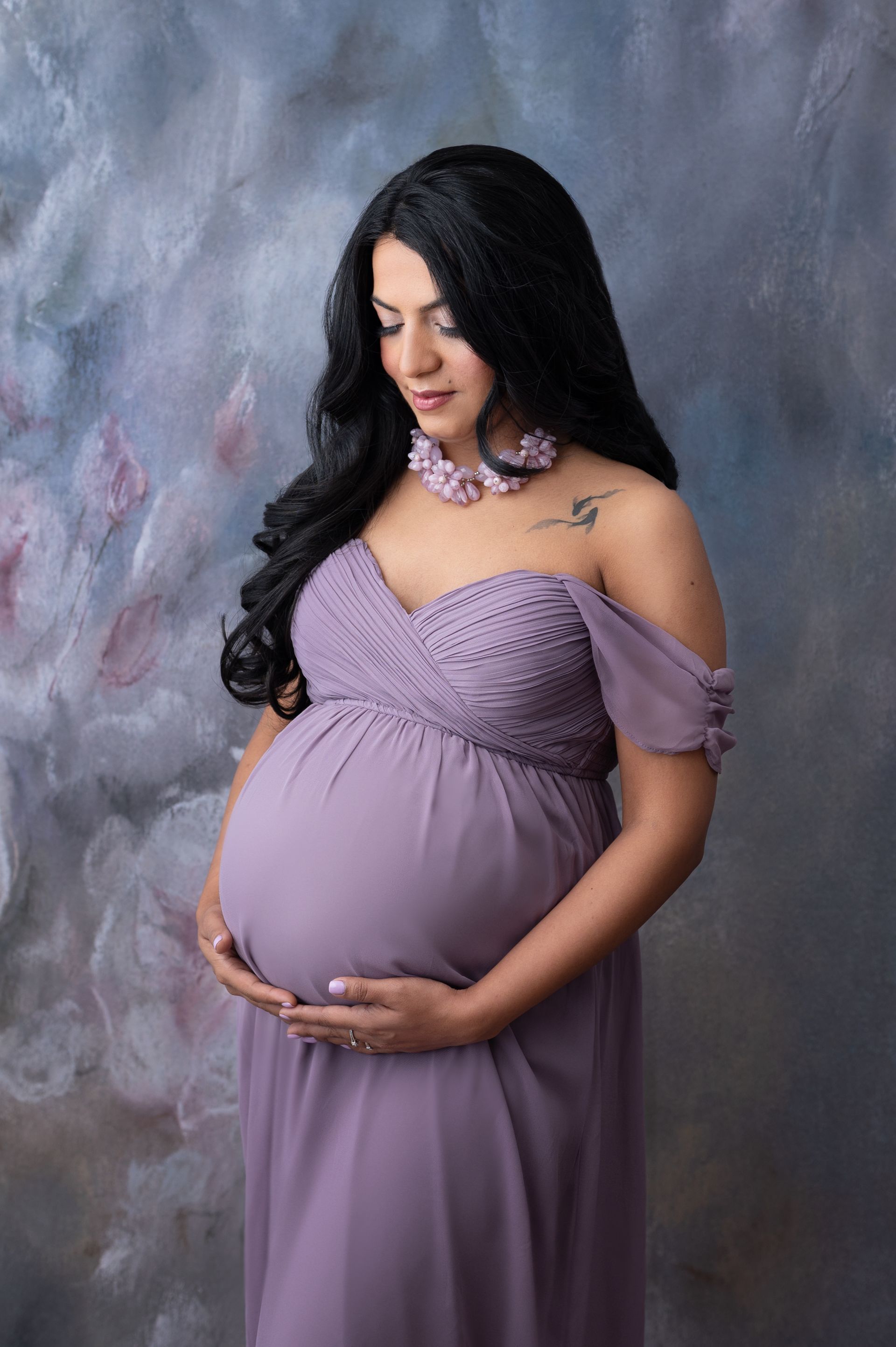 a pregnant woman in a purple dress is holding her belly .