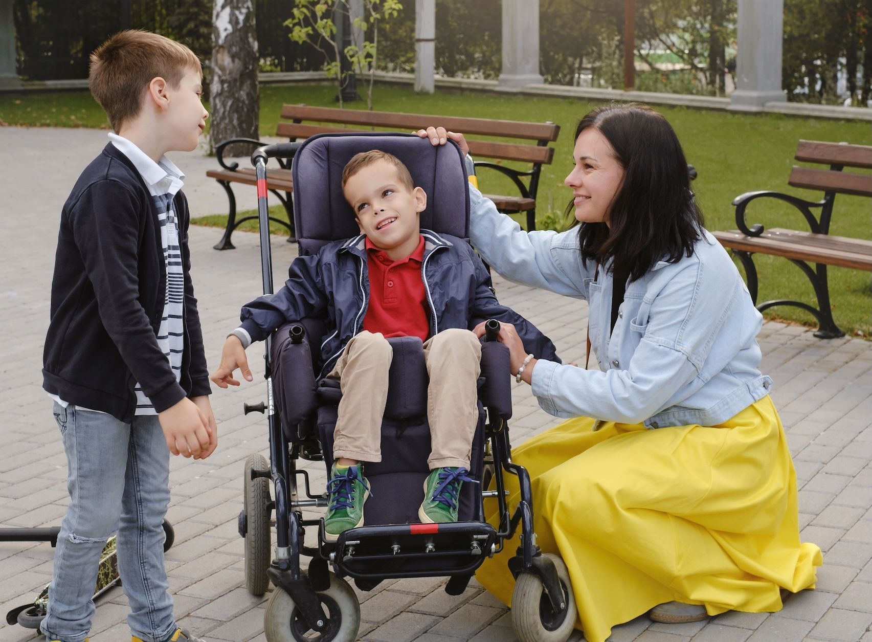 Boy with cerebral palsy in a wheelchair communicating with his mother and brother