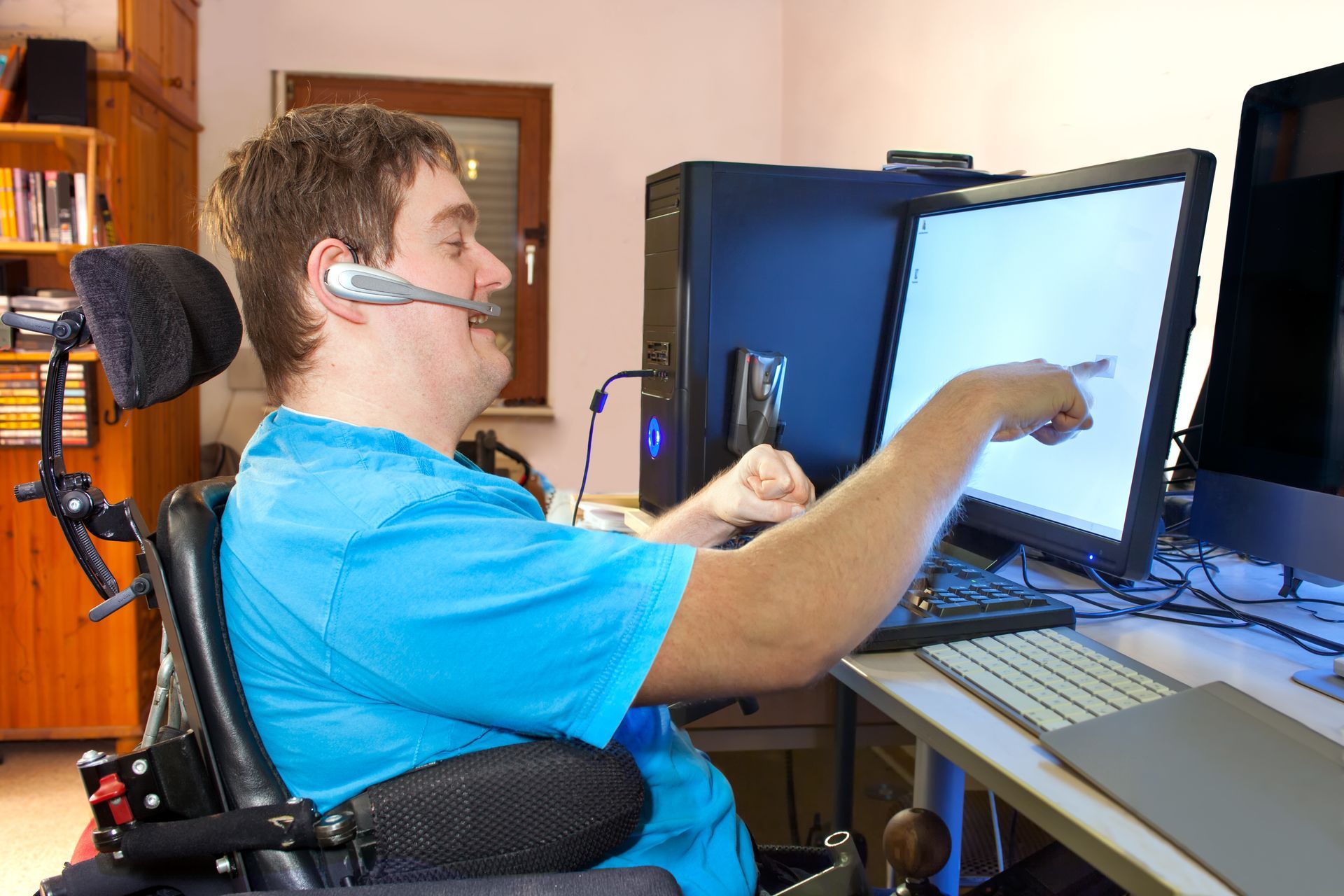Man with Cerebral Palsy communicating using a headset and pointing at a computer screen