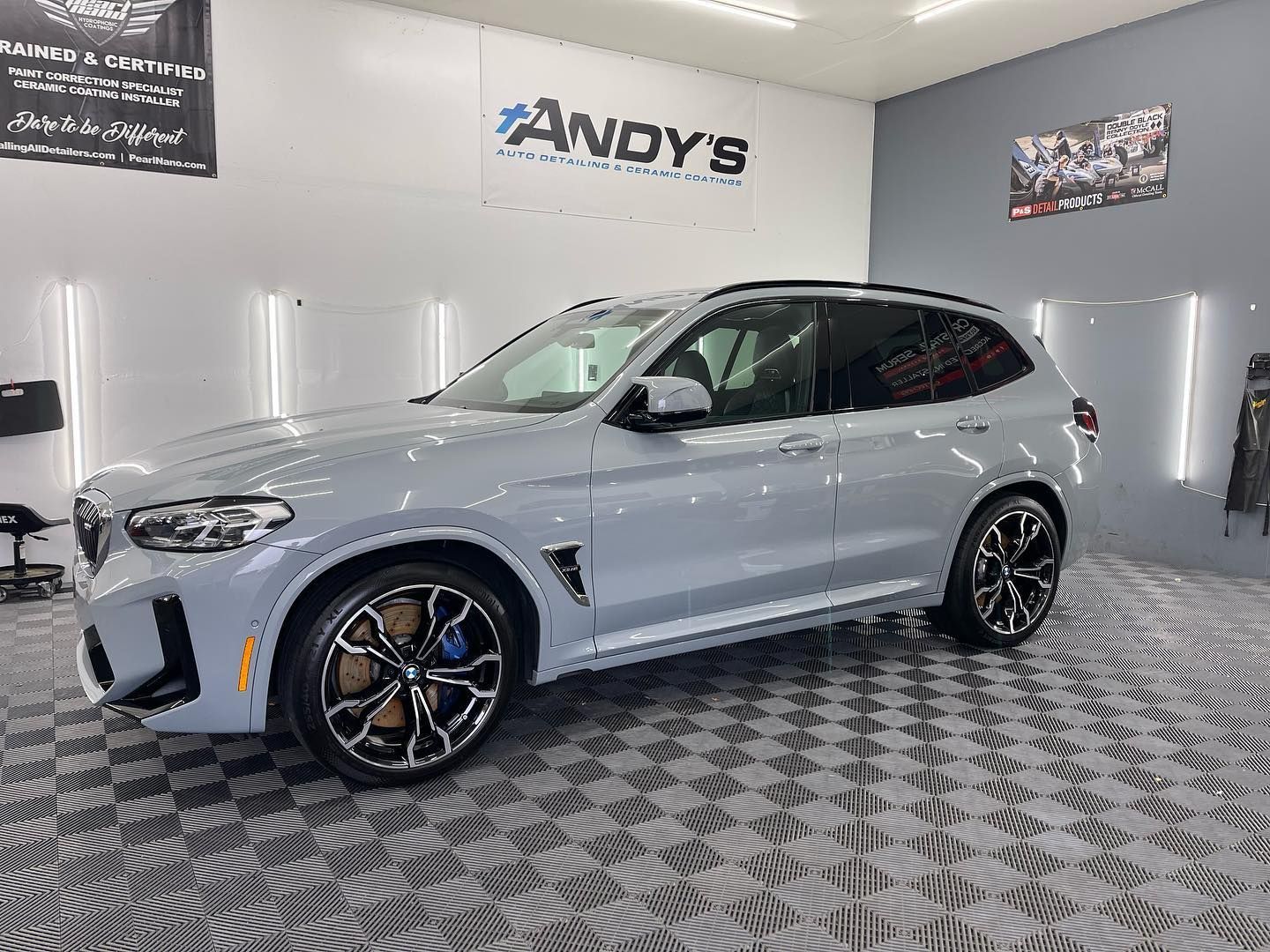 Light gray BMW SUV in a detailing shop, black and brown rims.