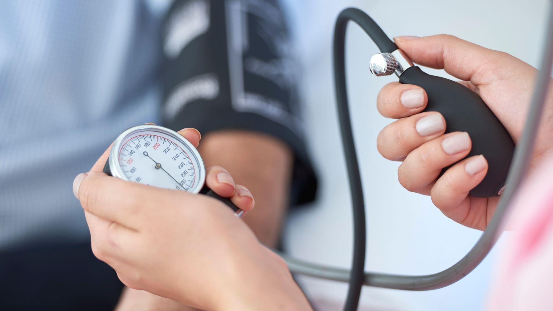Nurse taking a patient's blood pressure with a stethoscope and gauge, indoors.