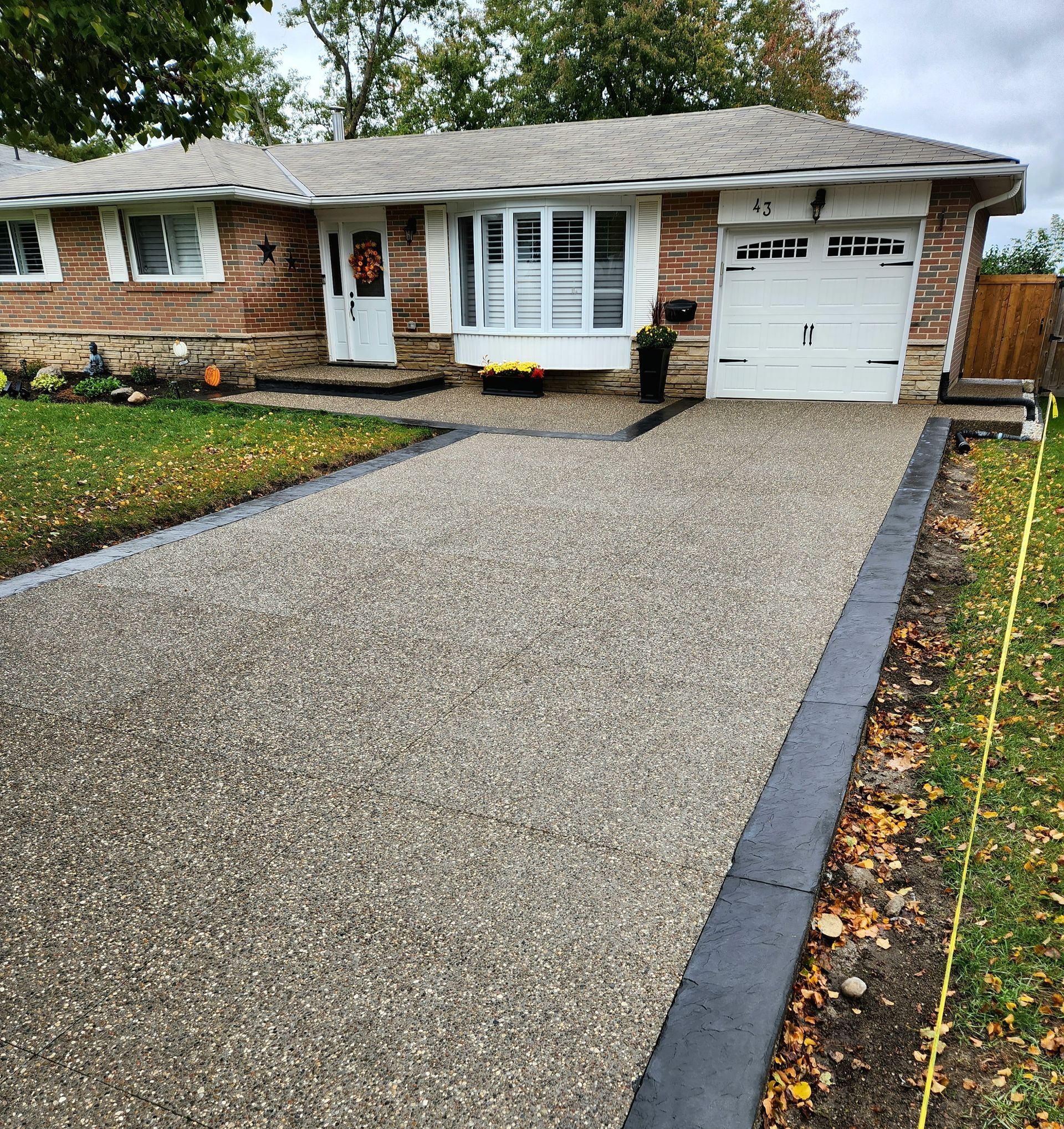 A concrete walkway leading to a house with a bench and a wagon wheel.
