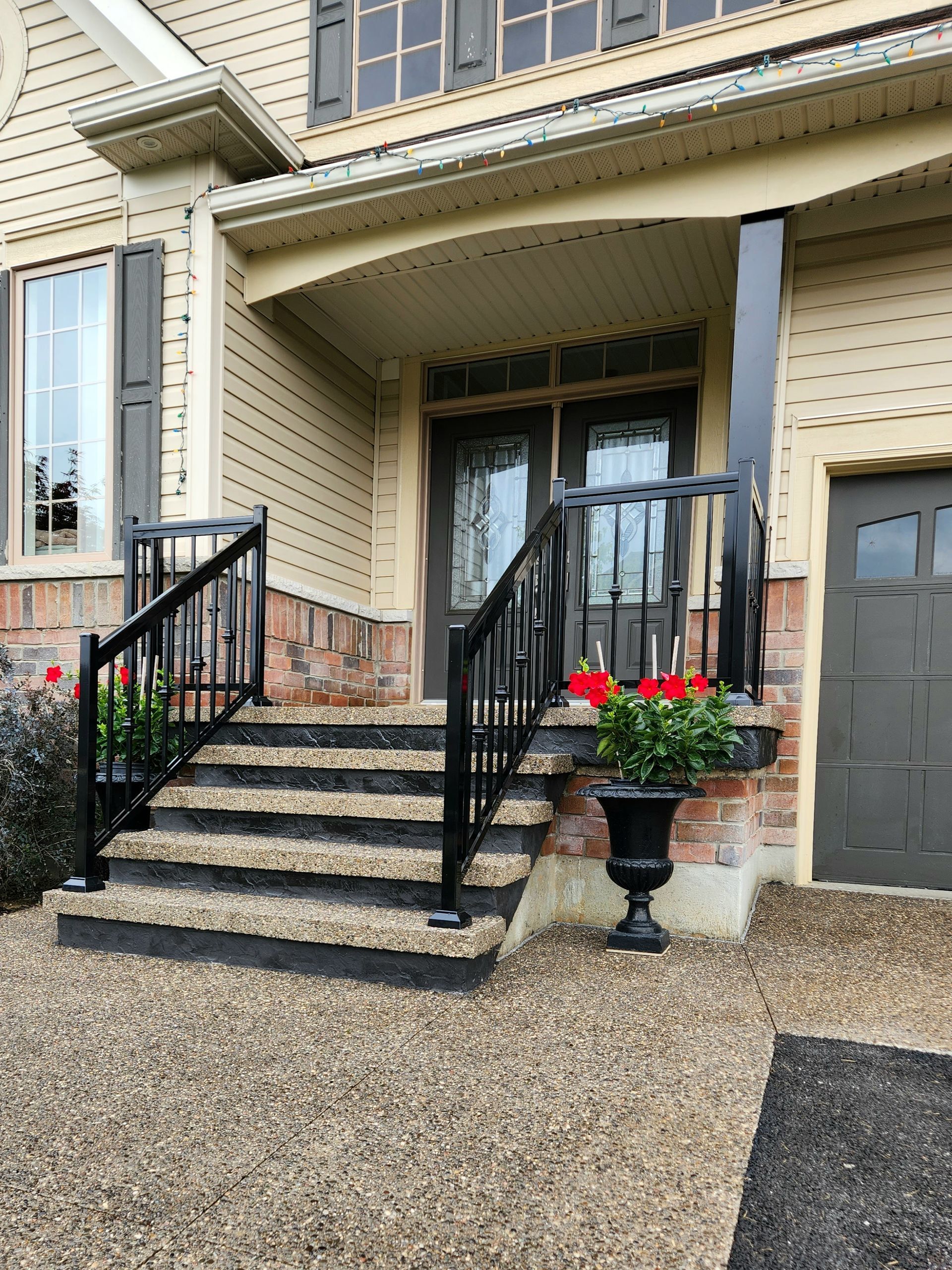 A concrete deck with a wooden railing is in front of a house.