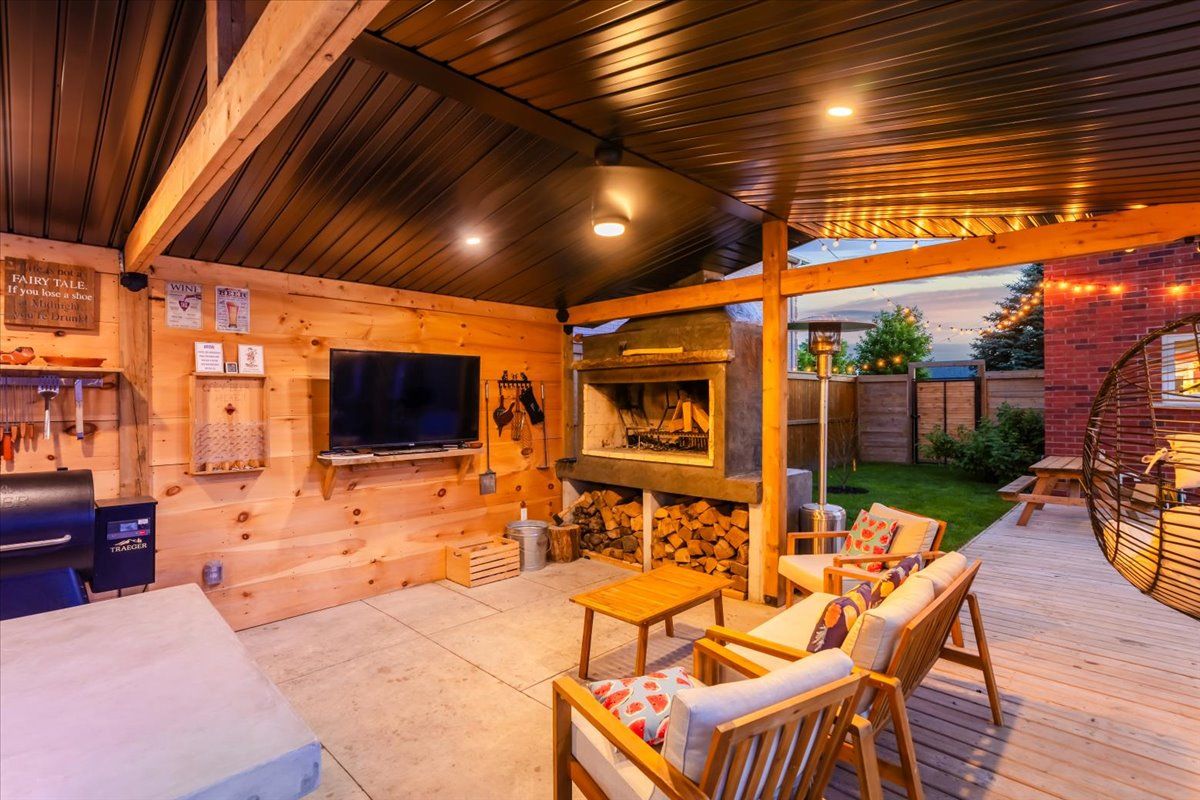 A living room with a fireplace , chairs , a table and a flat screen tv.