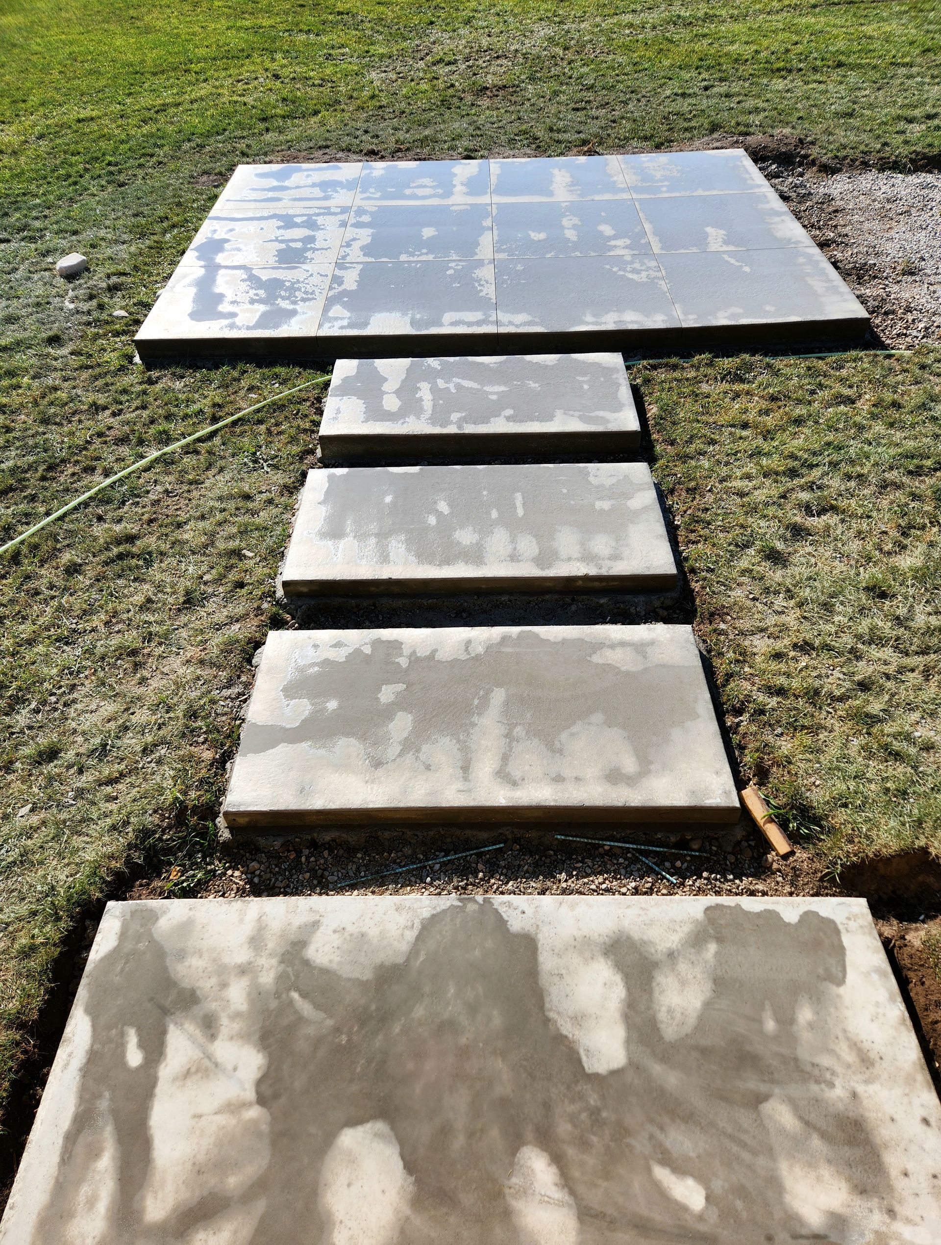 A concrete walkway is being built in the grass.